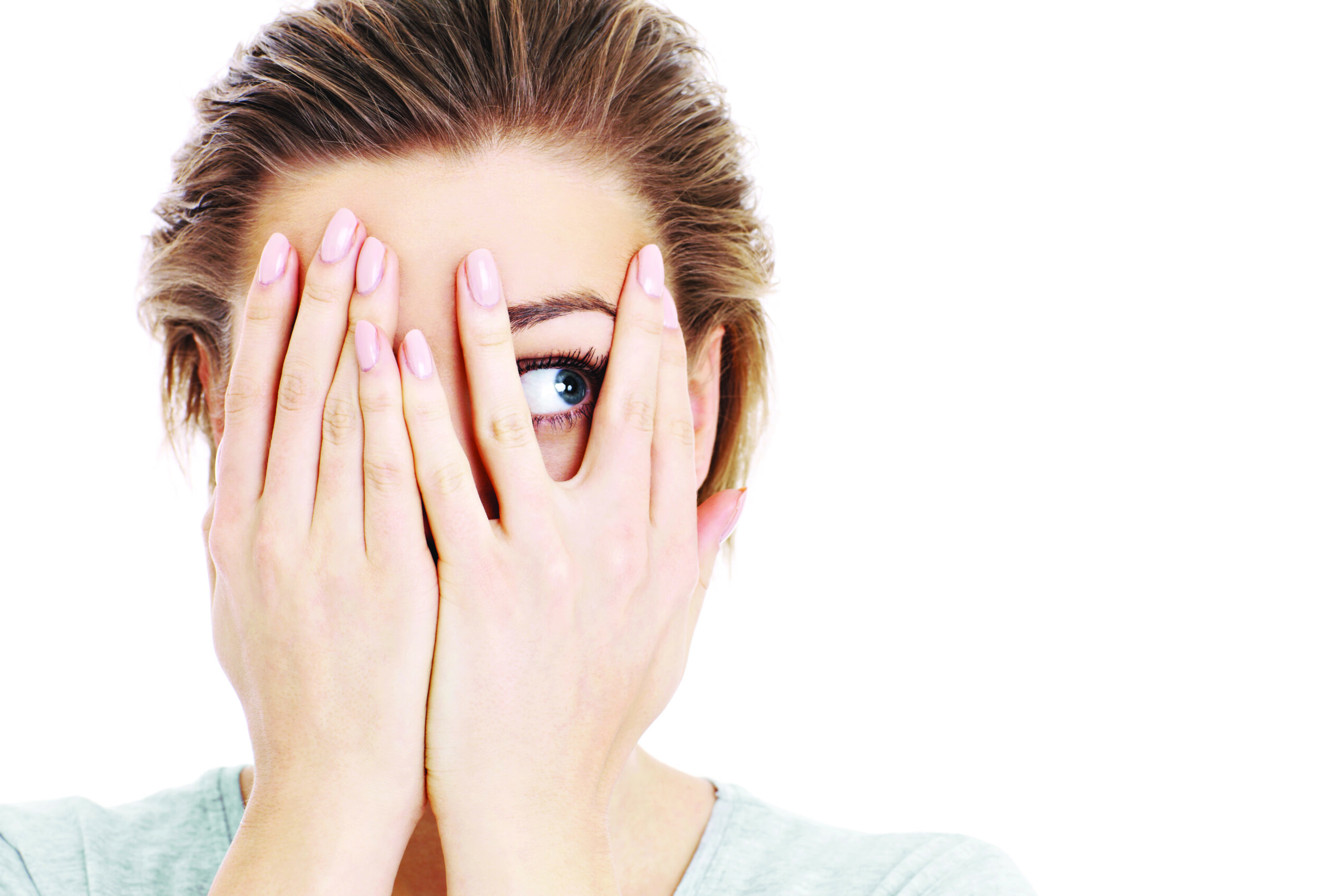 Woman playfully covering part of her face with her hands, revealing her eyes and showcasing defined, beautifully tinted eyebrows.